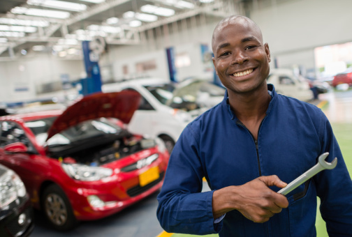 Mechanic at a car garage holding tools