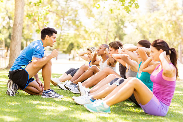 istock Personal Trainer Motivating People In Doing Sit-Ups At Park 509322813