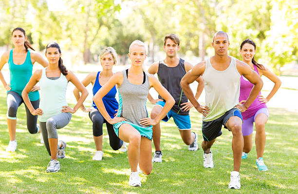 Fitness Class Performing Stretching Exercise In Park Full length portrait of multi-ethnic fitness class performing stretching exercise at bootcamp workout class in park. Horizontal shot. military camp stock pictures, royalty-free photos & images