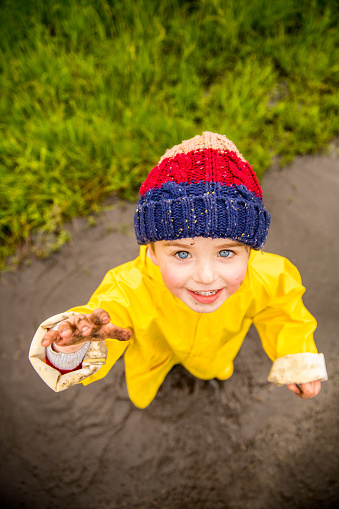 Young Boy Playing Outside in Puddles with muddy hands