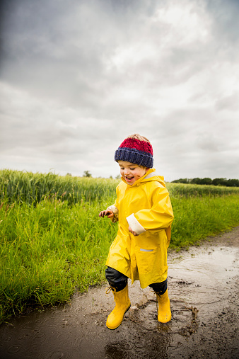 Happy Little Boy running through puddle after rain