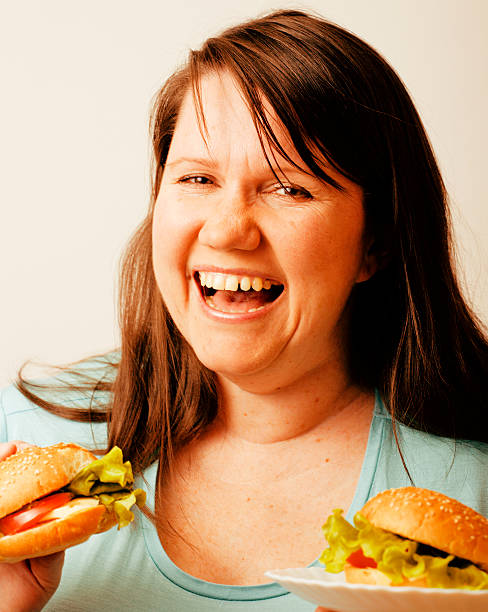 istock fat white woman having choice between hamburger and salad 509344237