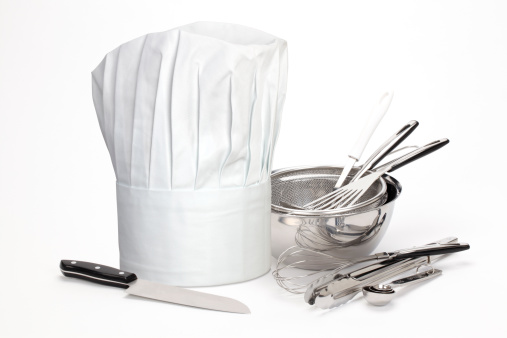 A chefs hat and utensils on a white background