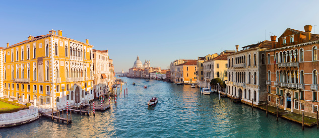 Tranquil Venetian canal scene with reflection, gondola and bridge, Venice at sunrise, Italy