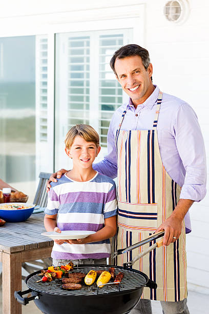istock Father And Son Standing In Front Of Barbecue On Patio 509345565