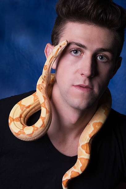 istock Colour image of man with snake, looking at camera. 509346652