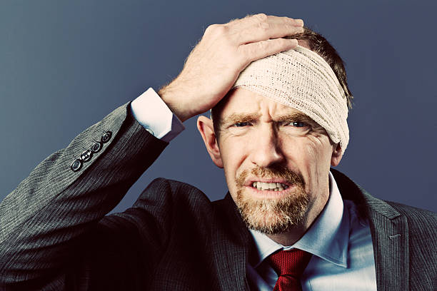 istock Wincing businessman holds bandaged head, looking unhappy 509347231