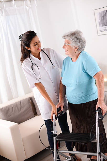 istock cheerful young rehab nurse helping elderly woman using walker 509349749