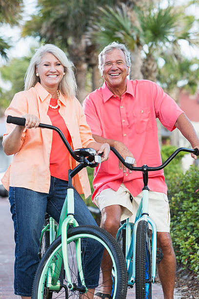 matura coppia biciclette equitazione in vacanza - mature adult bicycle senior adult heterosexual couple foto e immagini stock