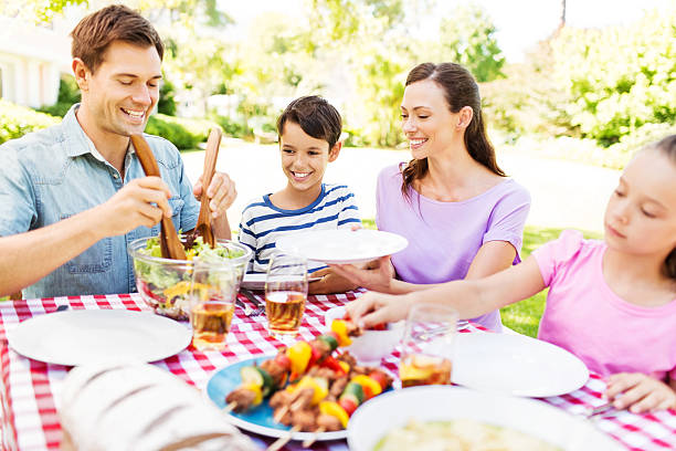 istock Man Serving Salad To Family At Lunch Table 509350221