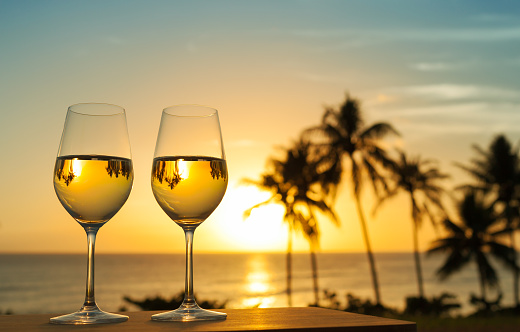 Romantic glass of wine setting by the beach against a beautiful sunset.