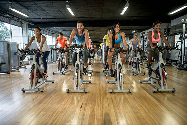 Group of people exercising at- the gym Group of people exercising at the gym in a exercising class - healthy lifestyle concepts spin bike stock pictures, royalty-free photos & images