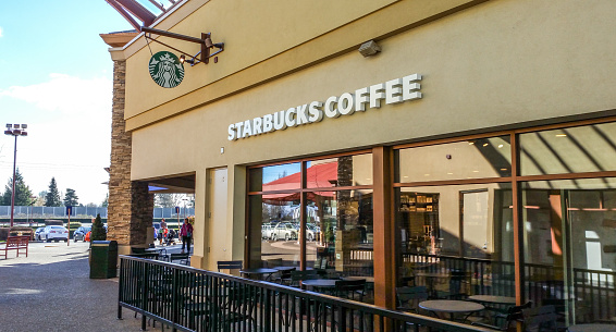 Woodburn, OR, USA - February 2, 2016: Starbucks locations serve hot and cold drinks, whole-bean coffee, microground instant coffee known as VIA, espresso, caffe latte, full- and loose-leaf teas including Teavana tea products, Evolution Fresh juices, Frappuccino beverages, pastries, and snacks; some offerings (including their Pumpkin Spice Latte) are seasonal or specific to the locality of the store. Many stores sell pre-packaged food items, hot and cold sandwiches, and drinkware including mugs and tumblers; select 