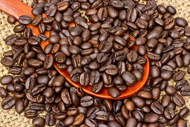 istock Coffee beans and wood spoon on vintage linen background 509362379