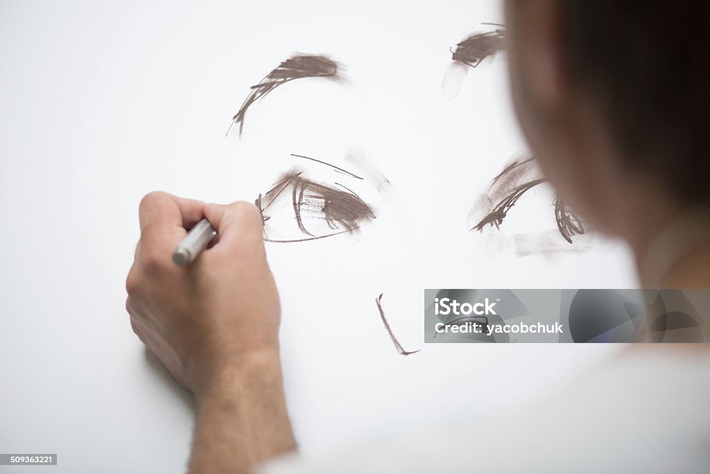 Painter and his art Painter drawing the picture with the lead pencil on the big white sheet of paper lying on the floor Abstract Stock Photo