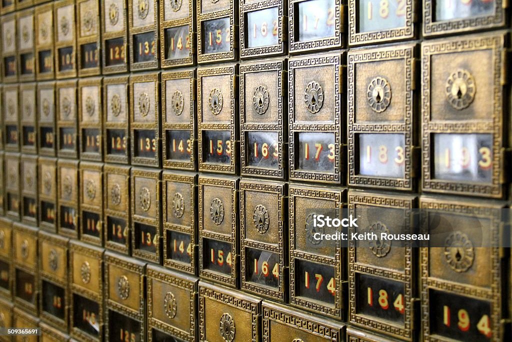 Old-World Wall of PO Boxes Several rows of sunlit old-world brass post office boxes line the wall. Architectural Column Stock Photo