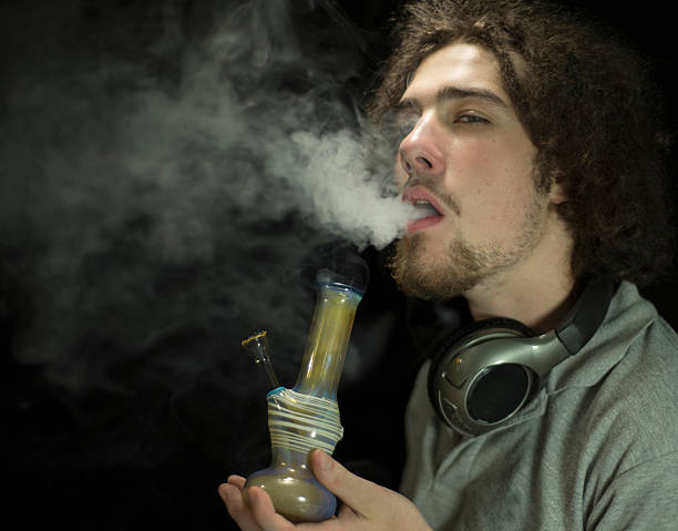 Getting high smoking a bong Young adult smoking marijuana in a bong bong stock pictures, royalty-free photos & images