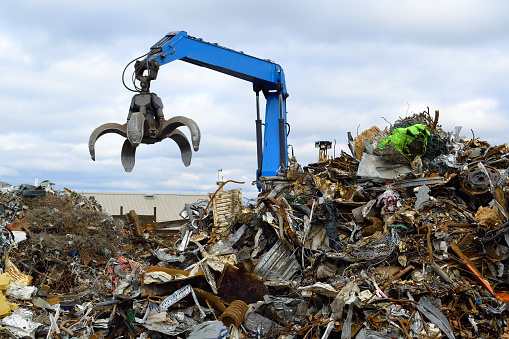 Blue hydraulic Clow Crane used for picking up scrap metal at recycling yard