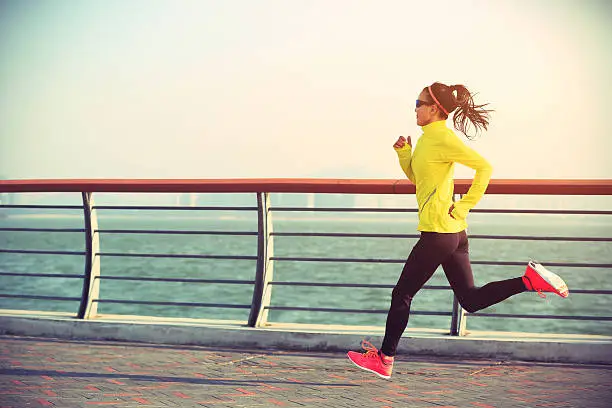 Photo of young fitness woman runner running on seaside