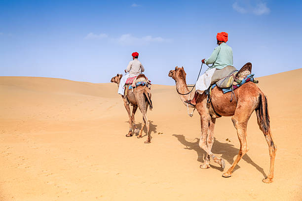 istock Indian men riding camels on sand dunes, Rajasthan, India 509369016