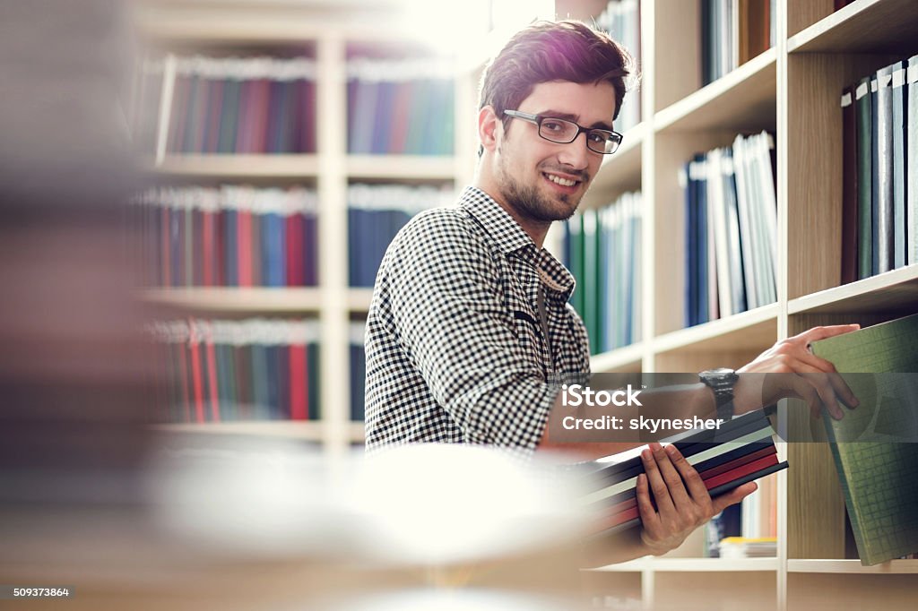 Lächelnd Student Sie Bücher in der Bibliothek und schaut an Ihre Kamera. - Lizenzfrei Bibliothek Stock-Foto