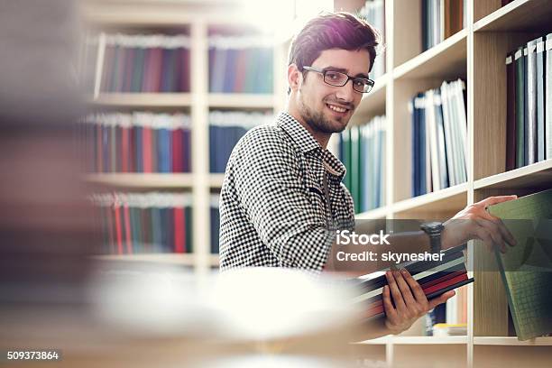 Lächelnd Student Sie Bücher In Der Bibliothek Und Schaut An Ihre Kamera Stockfoto und mehr Bilder von Bibliothek