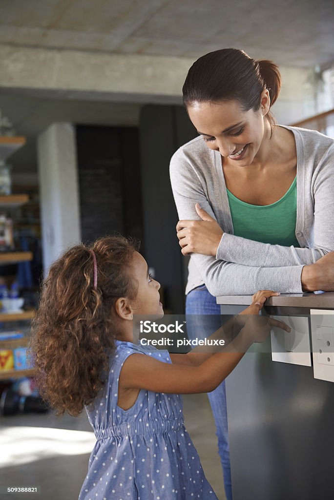 Learning to save energy early Shot of a little girl turning an appliance off at the wall while her mother looks on Domestic Life Stock Photo