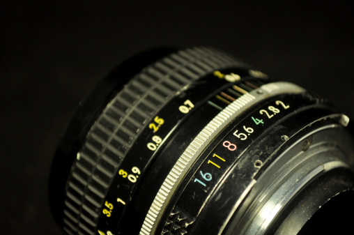 The lens diaphragm of manual and vintage camera on black background.