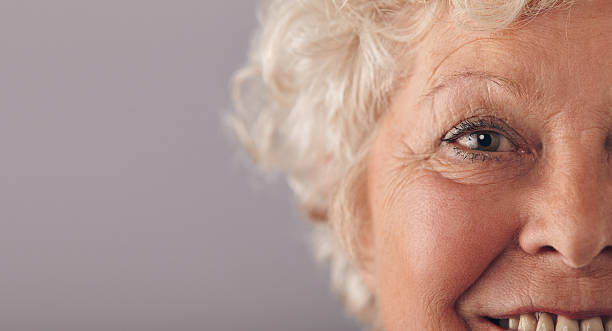 Part of senior woman face Part of senior woman face with focus on grey eyes. Old woman face close-up with copy space on against grey background. gray eyes photos stock pictures, royalty-free photos & images