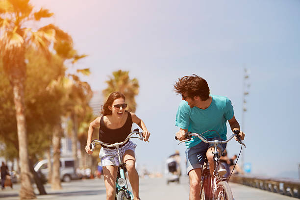 woman chasing man while riding bicycle - sommer stock-fotos und bilder