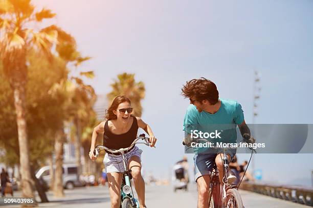 Woman Chasing Man While Riding Bicycle Stock Photo - Download Image Now - Summer, Cycling, Vacations