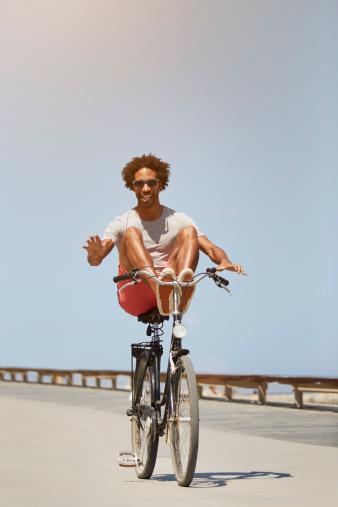 Full length of young man performing stunt on bicycle against clear blue sky