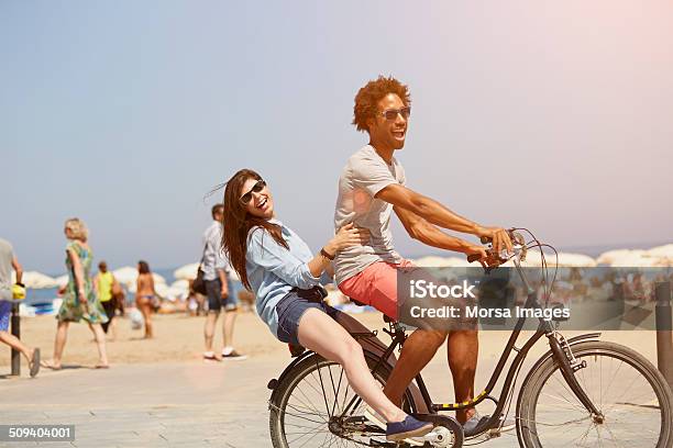 Couple Riding Bicycle At Beach Stock Photo - Download Image Now - Beach, Summer, Vacations