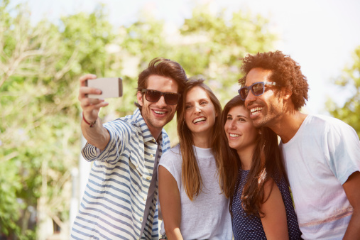 Happy multi-ethnic friends taking self portrait through mobile phone during summer vacation