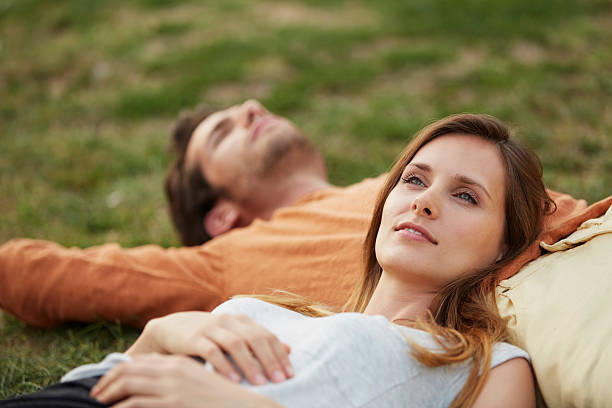 woman resting head on man's stomach at park - peace park 뉴스 사진 이미지