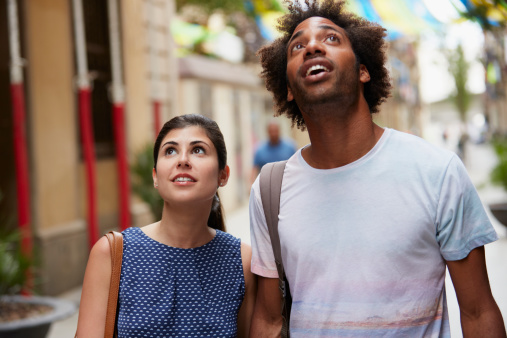 Surprised multi-ethnic couple looking up outdoors