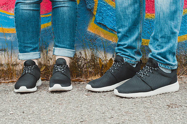 istock Black sneakers on couple's legs on the graffiti background 509408464
