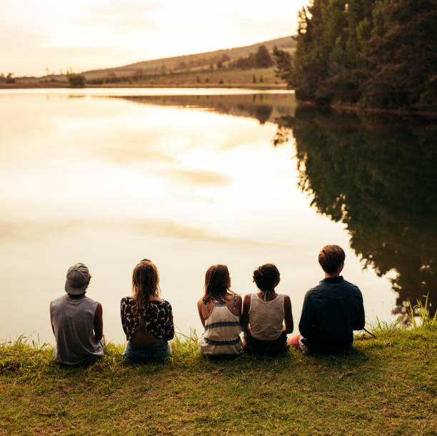 Group of young friends sitting by a lake