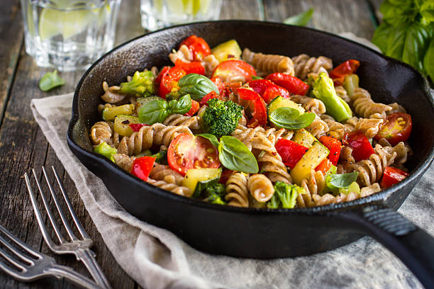 Whole wheat fusilli pasta  with vegetables Whole wheat pasta  with vegetables on cast iron pan whole wheat stock pictures, royalty-free photos & images