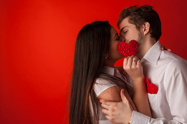istock Two young dates kissing behind paper heart 509411596