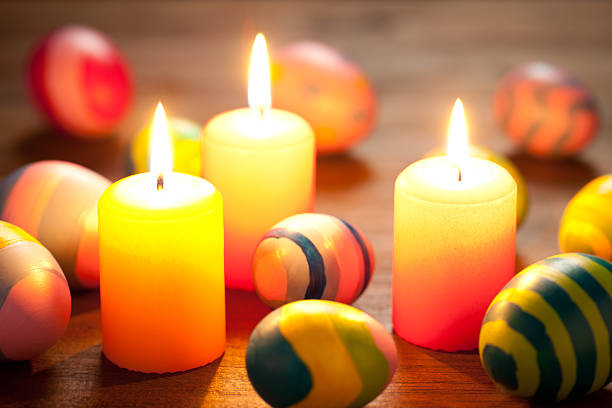 Colorful easter eggs and candles on old wooden table. This file is cleaned and retouched.