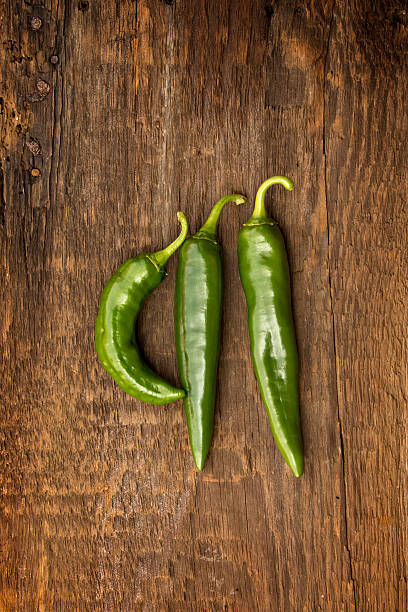 3 Anaheim Peppers on Barnwood Photo of 3 Anaheim peppers shot on a barn wood background. anaheim pepper photos stock pictures, royalty-free photos & images