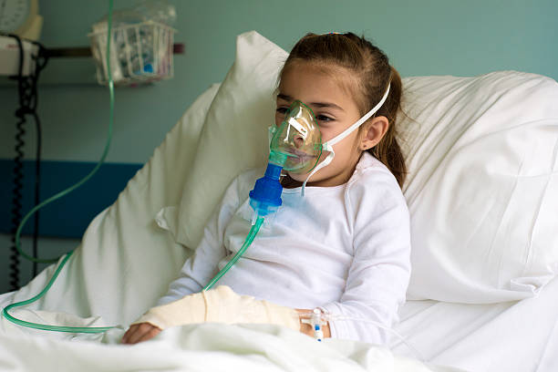 Little patient with inhalation mask Young little girl in the hospital bed using nebuliser to relieve the cough. Horizontal framing, shallow depth of field, adobeRGB photo. respiratory disease stock pictures, royalty-free photos & images