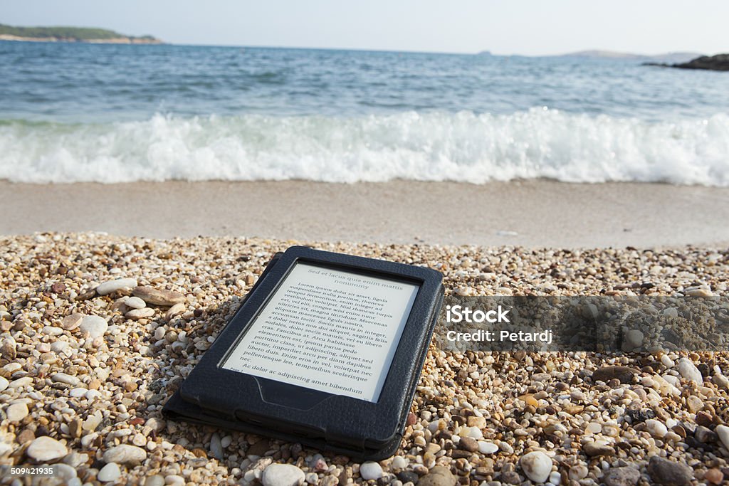 e-book reader on a beach with LOREM IPSUM text necessities for reading pleasure on sea side E-Reader Stock Photo