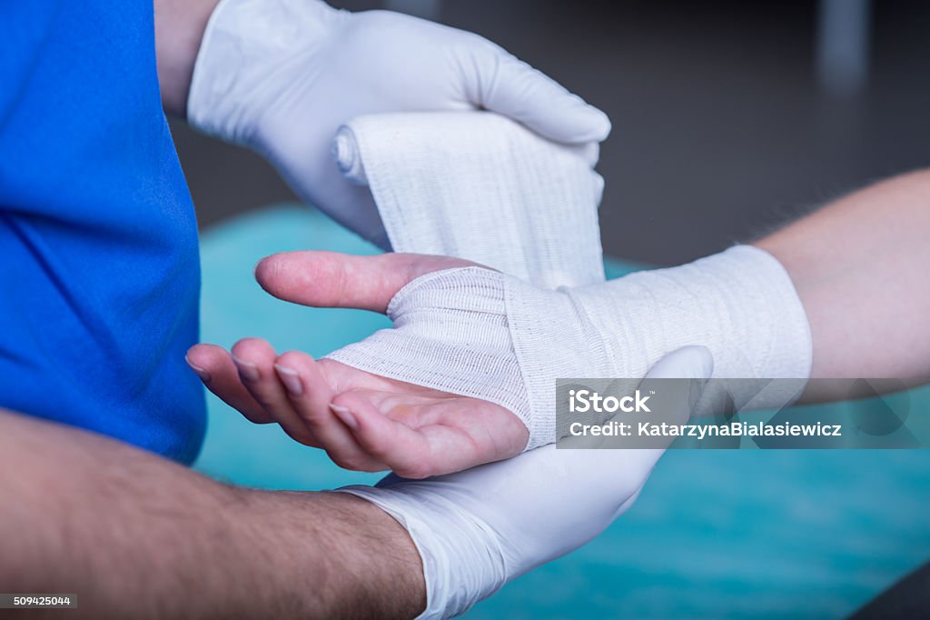 Bandaging a hand Close-up of male doctor bandaging a hand Wound Stock Photo