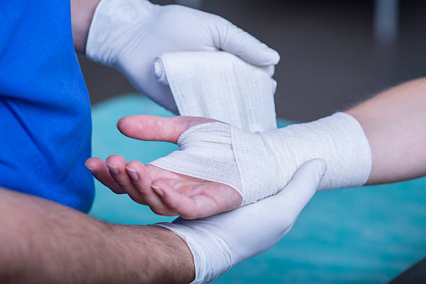 Bandaging a hand Close-up of male doctor bandaging a hand orthopedic cast stock pictures, royalty-free photos & images