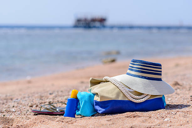 пляжная сумка и шляпа от солнца солнечный необитаемый на пляж - pattern blue sea sand стоковые фото и изображения