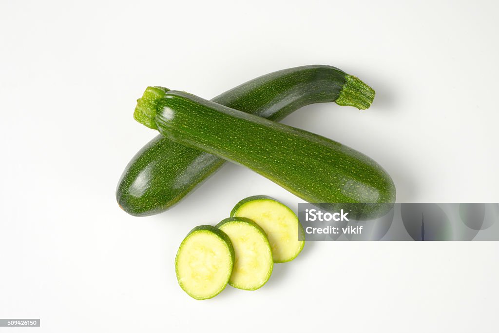 whole and sliced courgettes whole courgettes and courgette slices on white background Zucchini Stock Photo