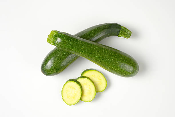 whole and sliced courgettes whole courgettes and courgette slices on white background courgette stock pictures, royalty-free photos & images