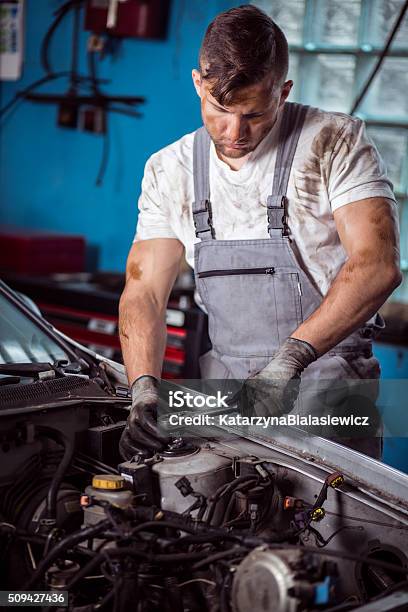 Mechanic Servicing Car Stock Photo - Download Image Now - Adult, Blue-collar Worker, Bonnet - Hat